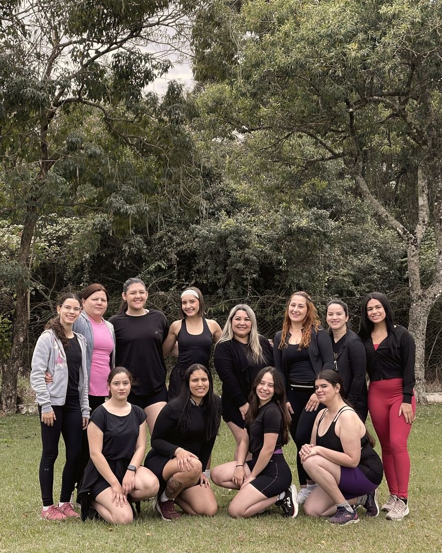 Grupo de mulheres posando junto em frente à mata