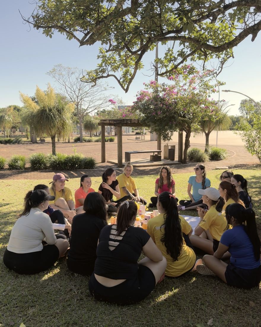 Roda de conversa com mulheres sentadas em círculo à sombra de uma árvore